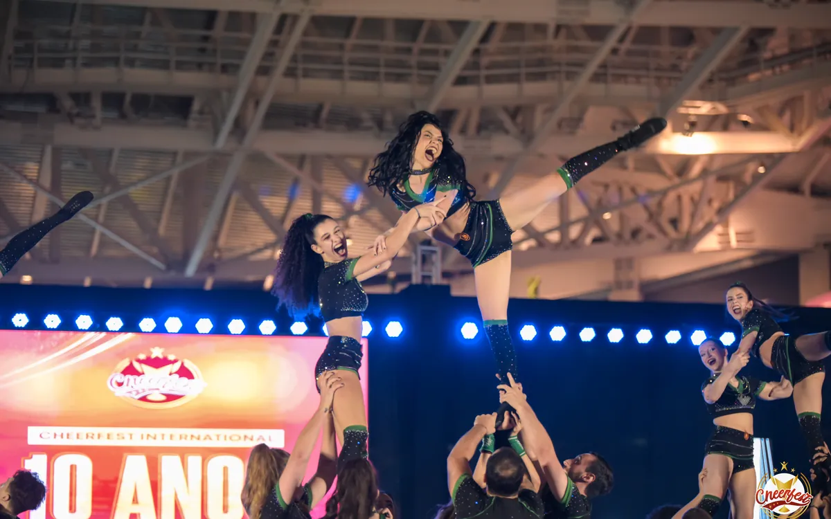 Atletas da Wolfpack em stunts no palco do Cheerfest International 2025, diante do telão dos 10 anos
